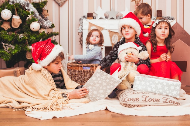 クリスマスの装飾の背景を持つサンタの帽子をかぶっている子供たち
