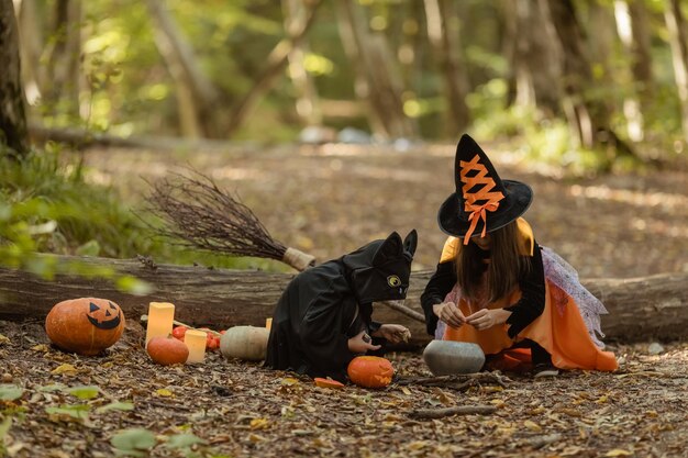 Children wearing witch and bat costumes and having fun in autumn park in Halloween Happy Halloween