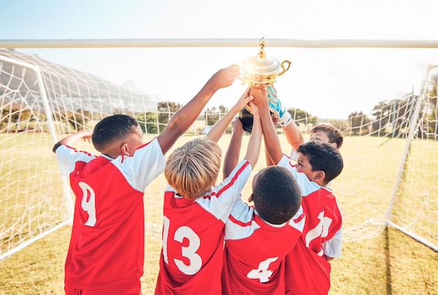 勝利の達成やフィールドでの試合を祝うトロフィーを持つ子供の勝者とチーム サッカー