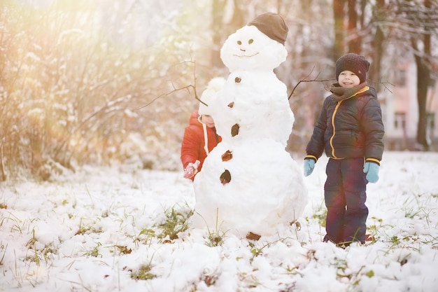 Children in winter park play with snow