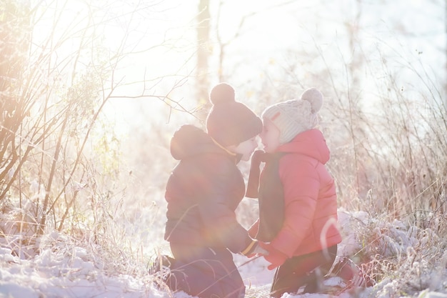 Children in winter park play with snow