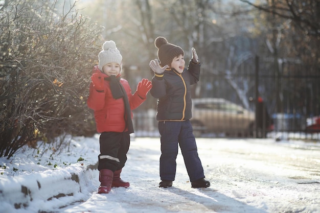 Children in winter park play with snow