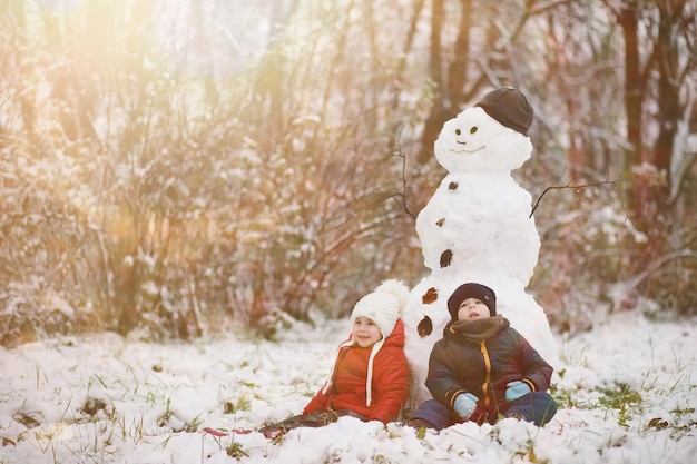 Children in winter park play with snow