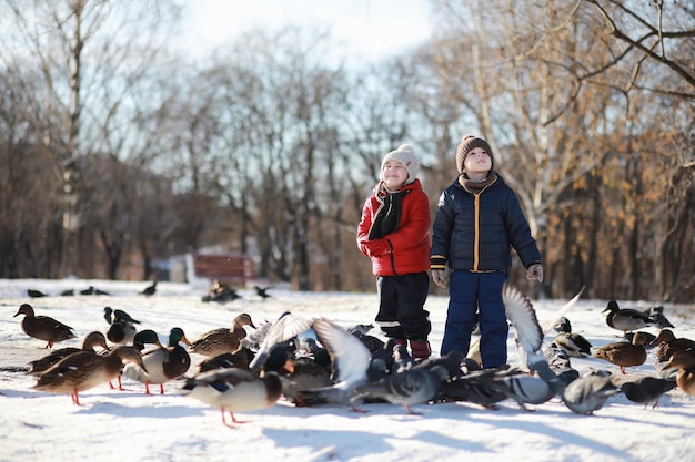 Children in winter park play with snow