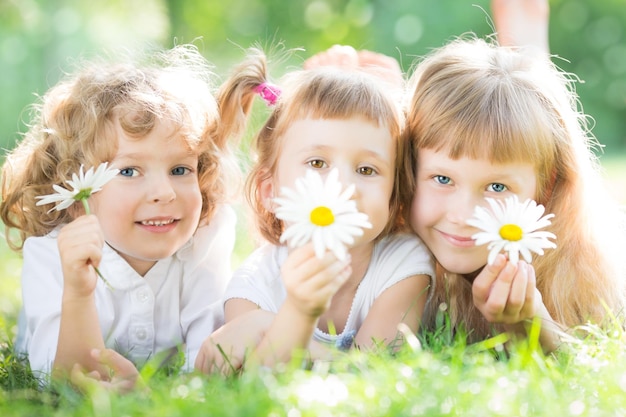 Foto bambini con fiori sdraiati sull'erba verde nel parco primaverile