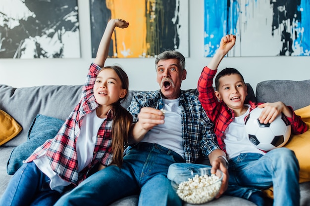 Children with grandfather cheering for a football game