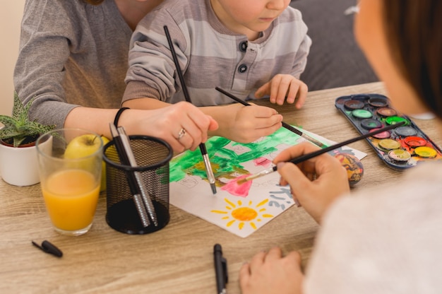 Foto i bambini con la mamma dipingono le immagini con colori ad acqua e pennello