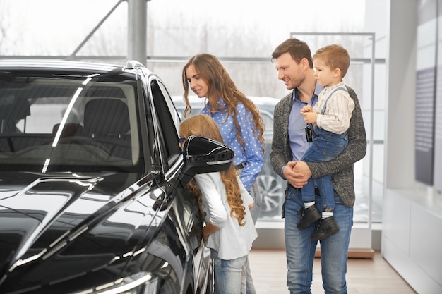 Children with parents looking at auto salon through window