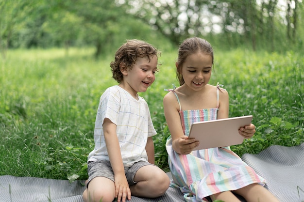 Children with a tablet outdoors kids speak by video call 