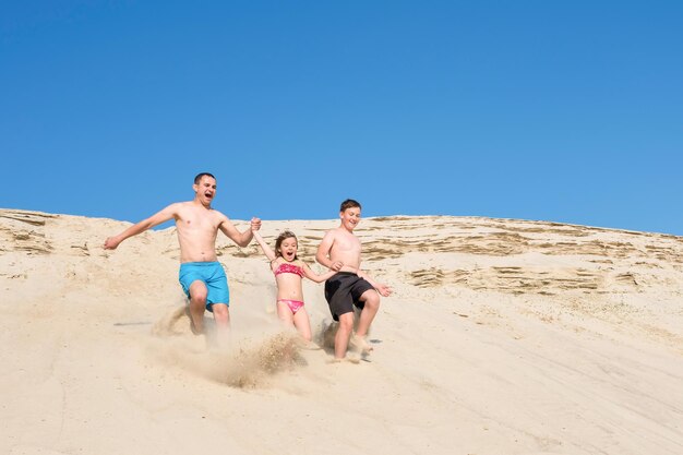 Children with their father run along the beach sand Family on vacation leisure sports lifestyle