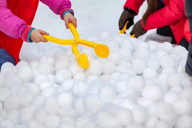 Photo children with yellow plastic snow ball maker for winter fun on holidays on snow