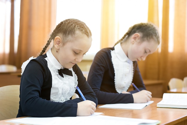 I bambini scrivono seduti al banco di scuola.