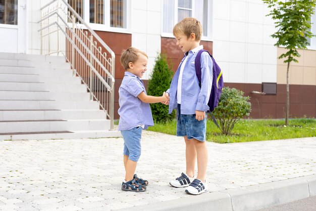 小学生以下の子供が学校の隣に立っている 休暇後の会議 学童の学校でのコミュニケーションの変更