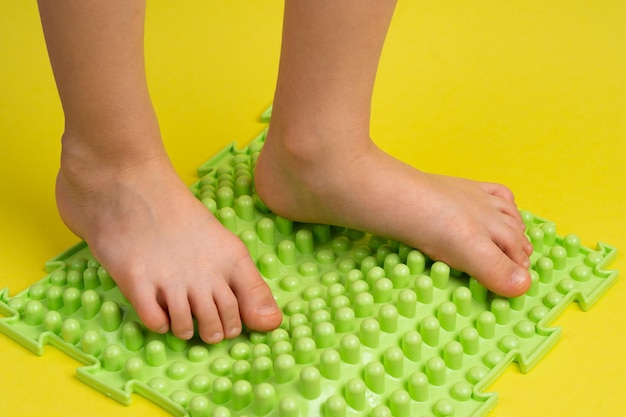 Children39s feet on a green orthopedic mat on a yellow background treatment and prevention of flat feet hallux valgus