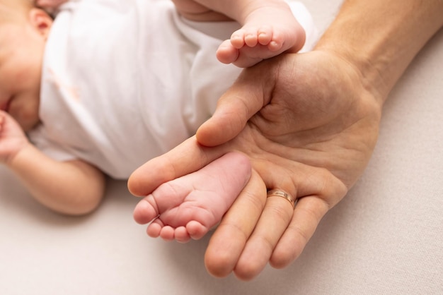 Children39s foot in the hands of mother father parents feet of\
a tiny newborn close up little baby legs mom and her child happy\
family concept beautiful concept image of motherhood stock\
photo