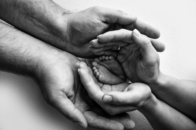 Children39s foot in the hands of mother father parents feet of\
a tiny newborn close up little baby legs mom and her child happy\
family concept black and white image of motherhood stock photo