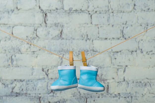 Photo childrens boots dry on a rope against a white brick wall