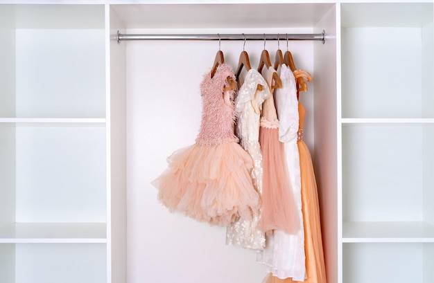 Childrens carnival dresses hang on wooden hangers in white closet