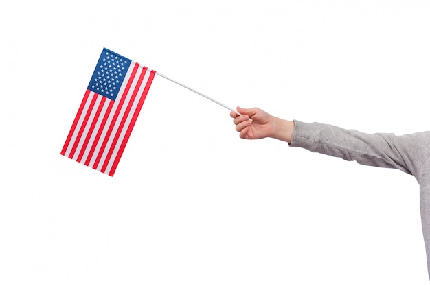 子供の手は、ホワイトスペースに分離された米国の旗を握っています。アメリカ合衆国の旗