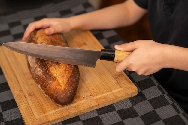 Photo childrens hands cutting bread on the table