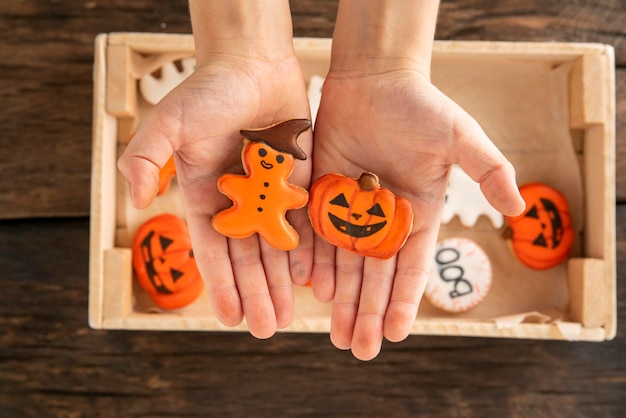 Childrens hands hold gingerbread in form of pumpkin and gingerbread man Festive cookies for Halloween
