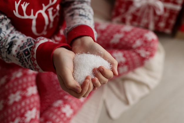 Le mani dei bambini tengono la neve a forma di cuore