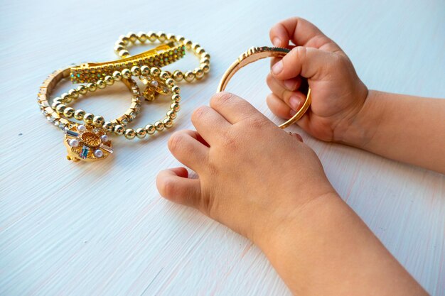 Childrens hands play with gold jewelry and bijouterie on white background concept of womens happines