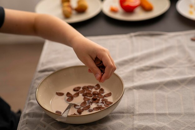 Foto mani dei bambini nel processo di colazione con cioccolato secco colazione con latte