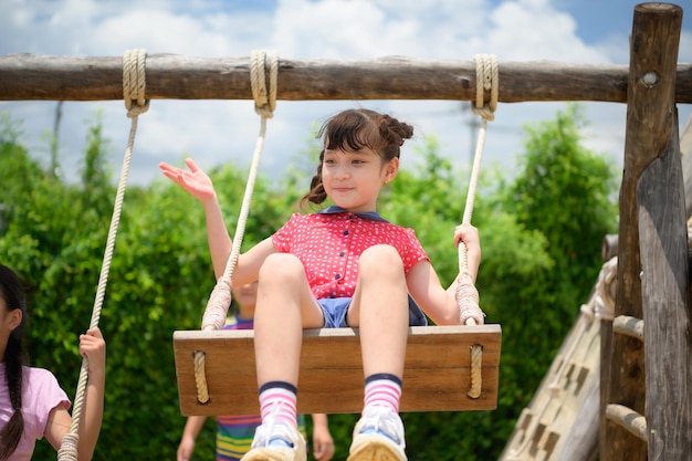 Childrens having fun swinging on a swing on a clear day