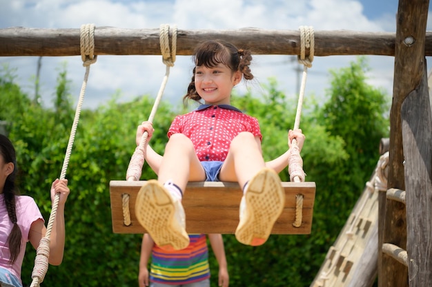 Childrens having fun swinging on a swing on a clear day