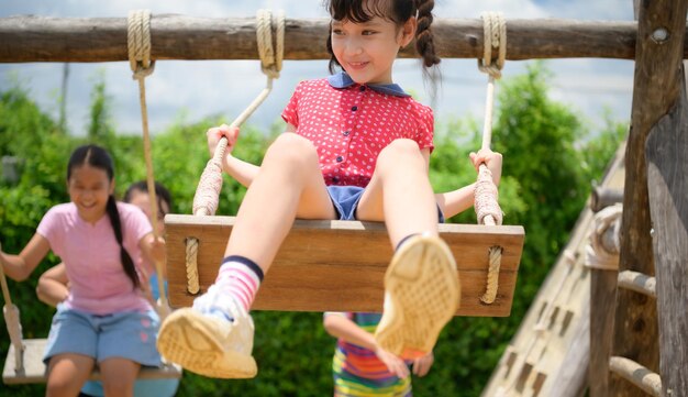 Childrens having fun swinging on a swing on a clear day