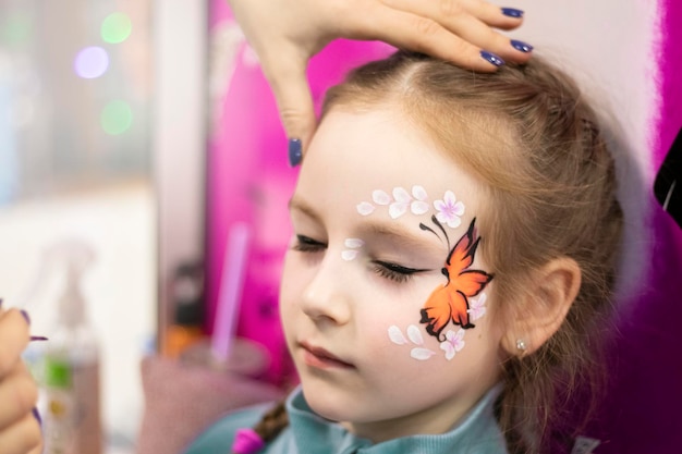 beautiful little girl with a painted fox on her face. face painting Stock  Photo