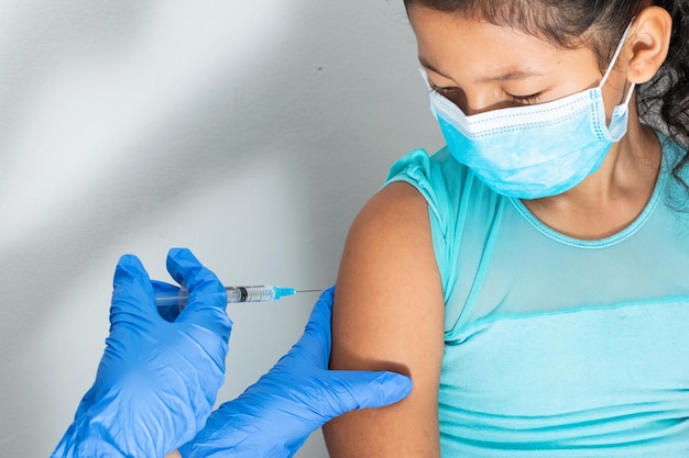 Photo childrens nurse injecting brown girls arm doctors hand with rubber gloves injecting covid-19