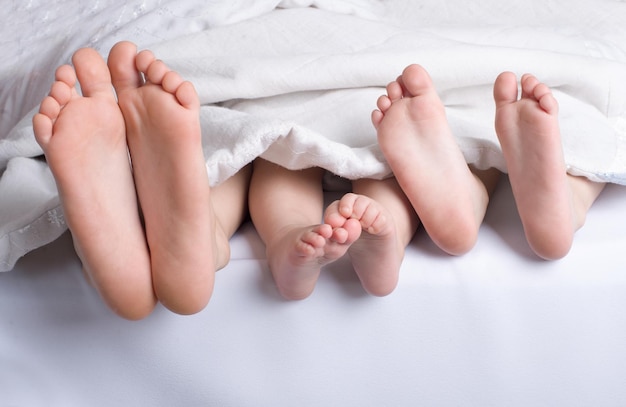 Childrens three pairs of legs peek out from under the blanket