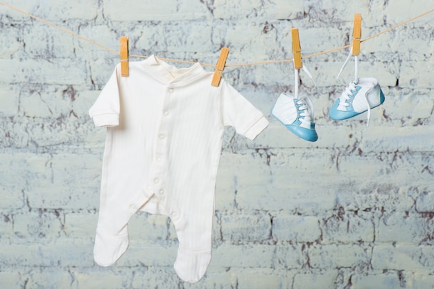 Photo childrens white body and blue shoes on a rope against a white brick wall