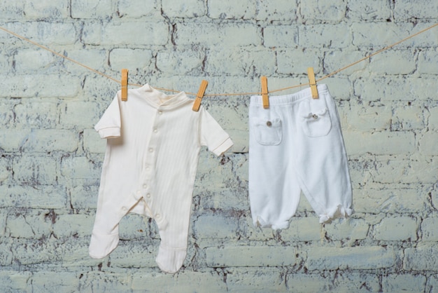 Childrens white body and pantyhose dry on a rope against a white brick wall