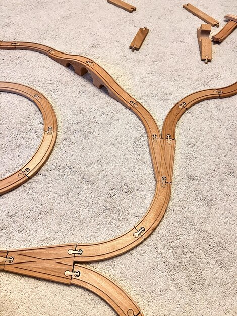 白い羊毛の絨毯に乗った子供用木造鉄道シルドはフォークで道路を作って遊んだ