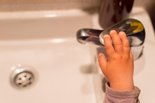 Photo childs hand opening faucet