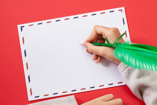 Childs hand with a feathershaped pen on a congratulatory envelope template for the designer