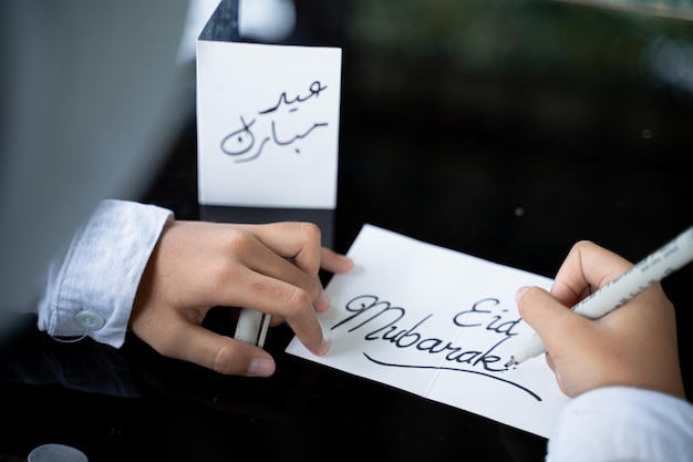 Photo childs hand writes a happy eid mubarak greeting card