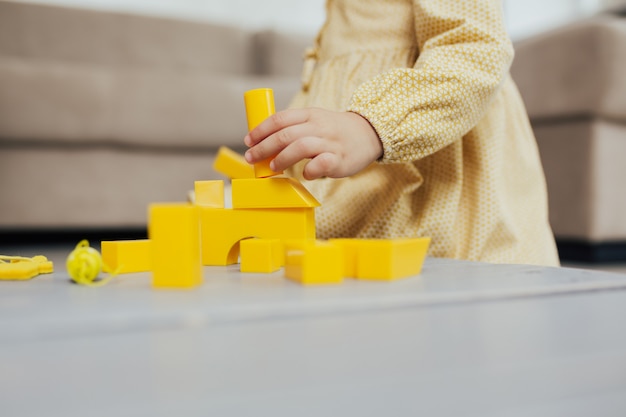 Photo childs hands playing with yellow cubes on grey wooden table