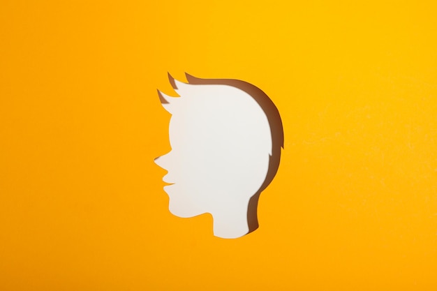 A childs head made of paper on a yellow background