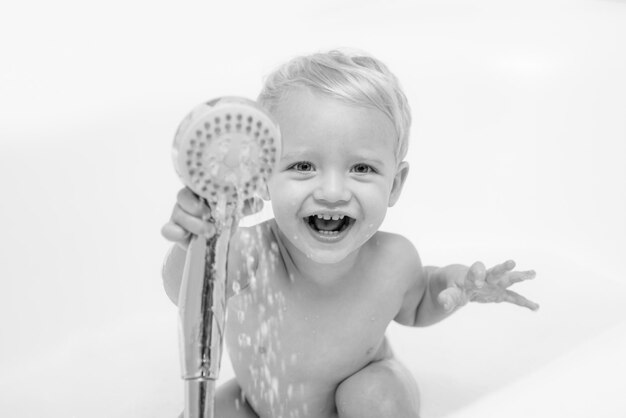 Childs hygiene. Funny baby playing with water and foam in a big kitchen sink. Health care and hygiene concept.