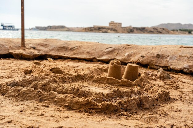 Photo childs sand castle on sandy beach near the water