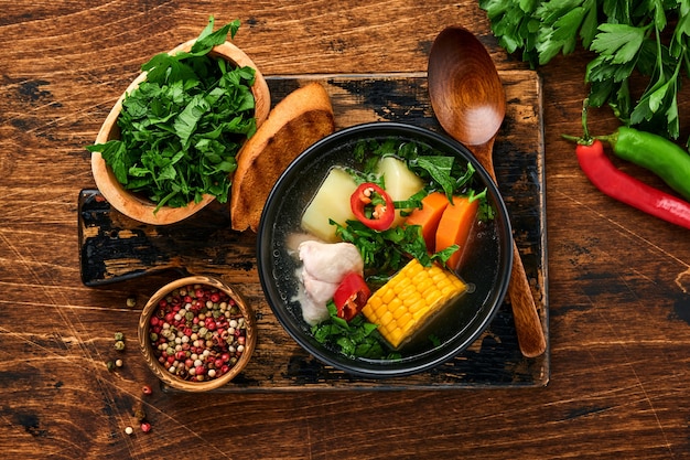 Chilean meat soup with pampkin, corn, fresh coriander and potatoes on old wooden table background. Cazuela. Latinamerican food.