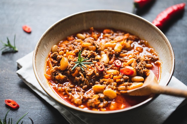 Chili con carne in bowl on dark background mexican cuisine\
chili con carne minced meat and vegetables stew in tomato sauce top\
view