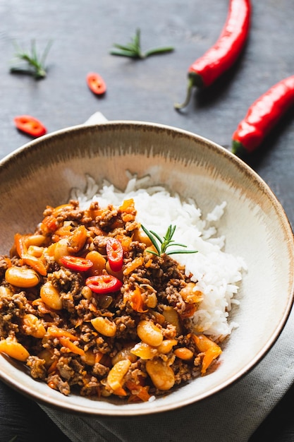 Chili Con Carne in bowl on dark background Mexican cuisine chili con carne minced meat and vegetables stew in tomato sauce Top view