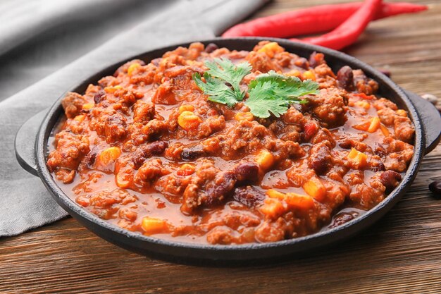 Foto chili con carne in padella su sfondo di legno