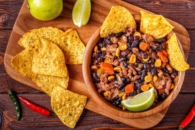 Chili con carne in kom met tortillachips op houten