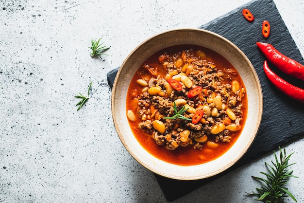 Chili Con Carne in kom op lichtgrijze steen of betonnen ondergrond Mexicaanse keuken Chili con carne gehakt vlees en groenten stoofpot in tomatensaus Bovenaanzicht